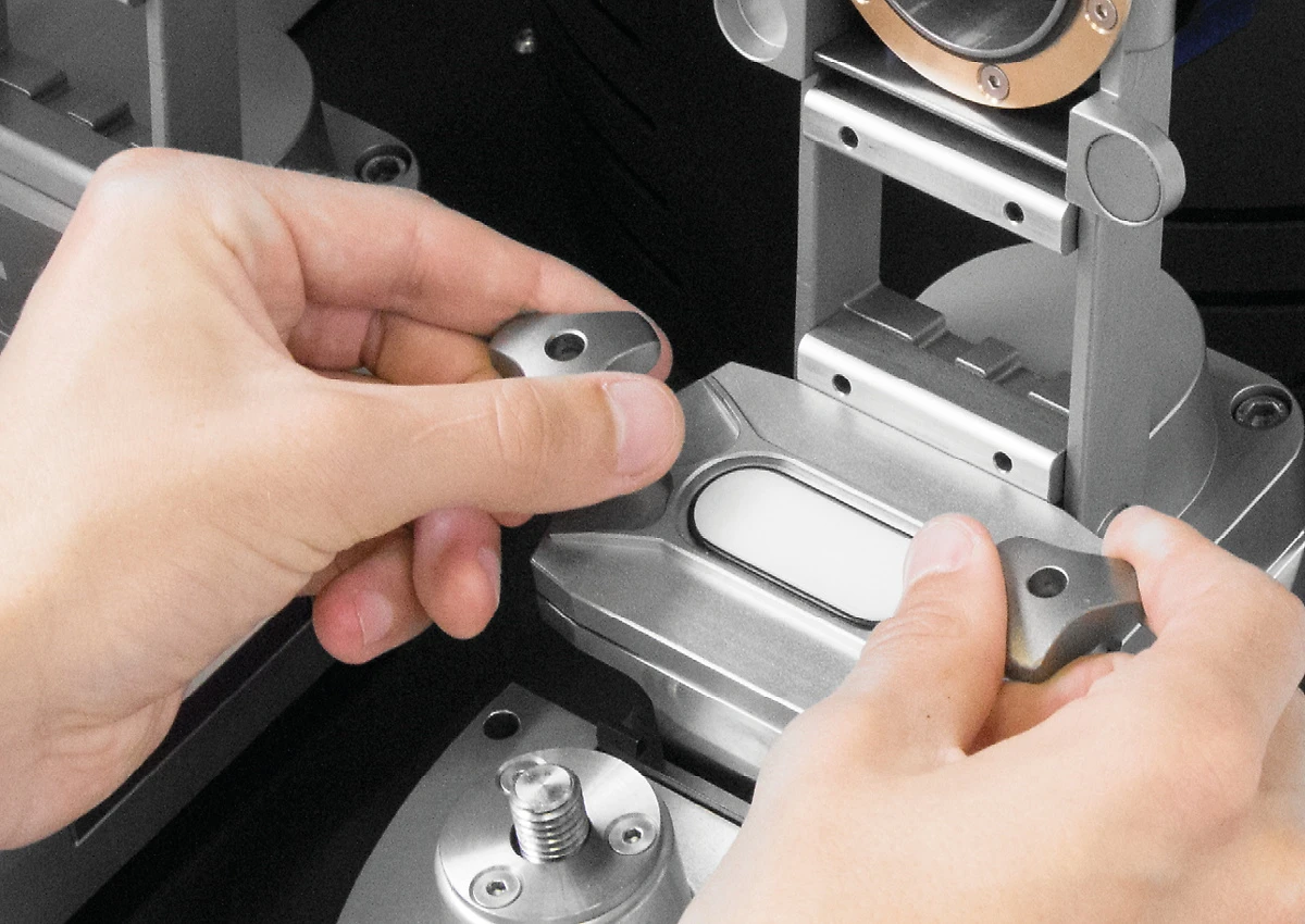 Hands inserting a grinding jar into the clamp of the Emax high energy ball mill