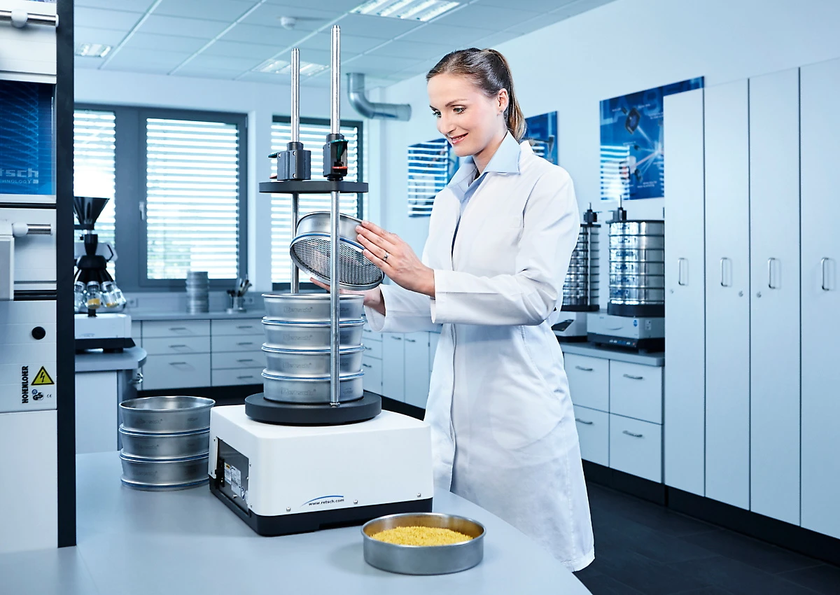 Lab technician placing a sieve stack on a vibratory sieve shaker